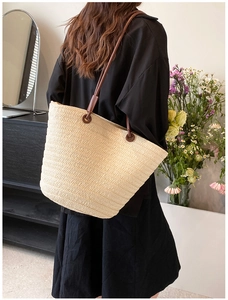 Detailed view of the woven straw shoulder bag with brown leather straps and texture