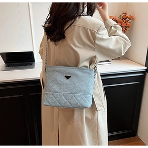 Detail of light blue nylon crossbody bag with diamond quilting and silver chain strap