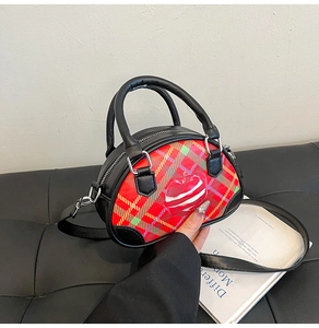 Detail der Vintage-Karo-Handtasche mit Apfeldruck auf schwarzem Ledersofa