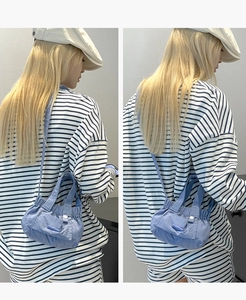 Detail view of light blue pleated mini bucket bag worn as a crossbody accessory