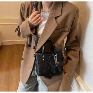 Détail d'un sac seau noir gaufré avec charm chiot et garnitures dorées élégantes