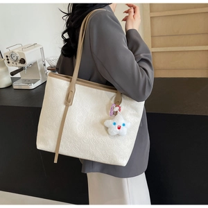 Detail of white embossed tote bag with sun and moon patterns and khaki shoulder straps