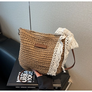 Close-up of woven straw bag detail featuring elegant white lace bow and brown leather strap