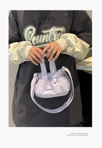 Detail view of mini light purple pleated nylon bucket bag held by model