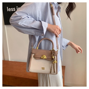 Detail of a vintage-style crossbody bag with gold animal buckle and leather texture