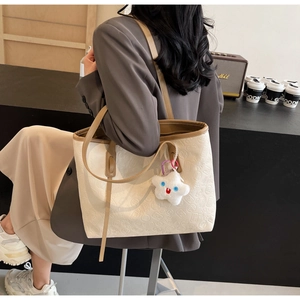 Model wearing a large embossed tote bag with mahjong patterns and star pendant