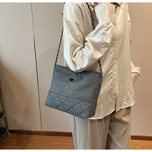 Close-up of dark grey square crossbody bag with chain strap and triangular metal logo