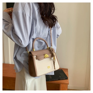 Detail of color-block crossbody bag with gold buckle on blue striped shirt outfit