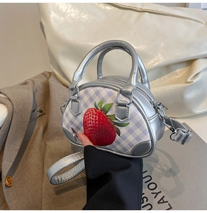 Detail der silbernen Metallic-Handtasche mit lila Karomuster und Erdbeerdruck