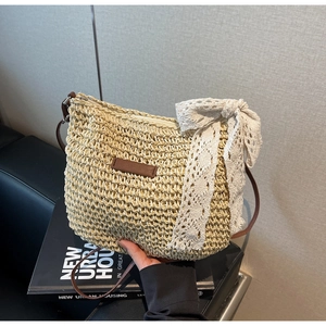 Close-up of woven straw bag texture featuring a large white lace bow and brown leather strap