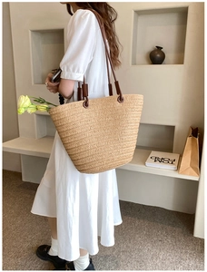 Detail of hand-woven straw tote bag with brown leather straps and large capacity