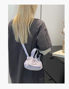 Detail of lavender drawstring bucket bag with pleats and slender crossbody strap