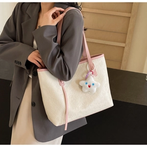 Detail of off-white embossed tote bag with pink straps and star plush pendant