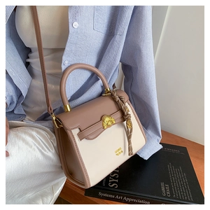 Detail of elegant two-tone crossbody bag with gold buckle and woven knot accent