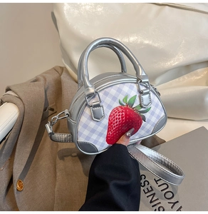 Detail der silbernen Karo-Mini-Handtasche mit Erdbeerdruck und metallischen Tragegriffen