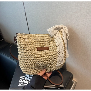 Detail of bohemian straw bucket bag featuring a large white lace bow and zip closure