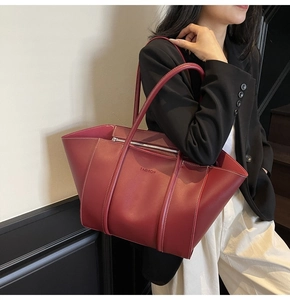 Detail of burgundy tote bag showing white contrast stitching and fashion embossing