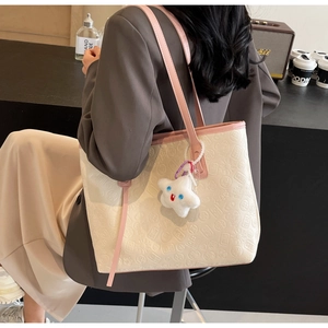 Detailed view of cream tote bag with traditional Chinese embossing and pink strap
