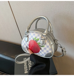 Details einer silbernen Handtasche mit Erdbeerdruck, lila Karo und Metallic-Finish