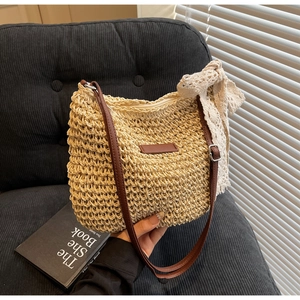 Detail of hand-woven straw shoulder bag with elegant lace bow and brown leather strap