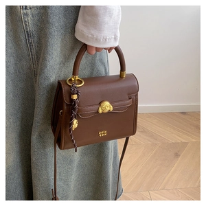 Detail of vintage brown leather crossbody bag featuring a gold dog-head buckle and strap