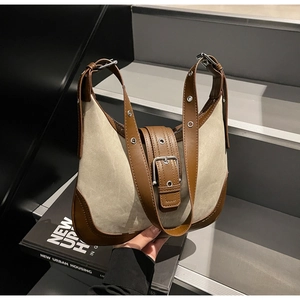 Détail du sac à bandoulière en toile et cuir avec œillets métalliques sur escalier
