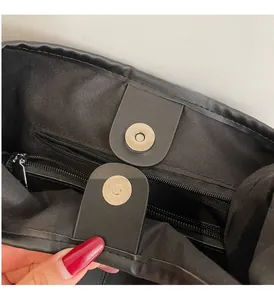 Detail of black leather tote bag featuring magnetic closure and premium hardware