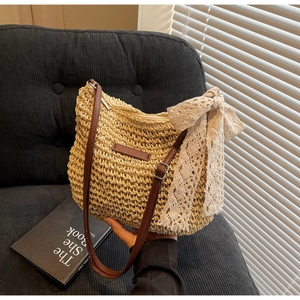 Detail of woven straw bucket bag with white lace bow and brown leather shoulder strap
