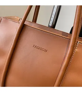 Detail of brown leather tote bag with white contrast stitching and Fashion embossed logo