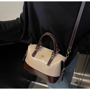 Detail of a chic Boston bag with contrast beige and brown leather and gold hardware