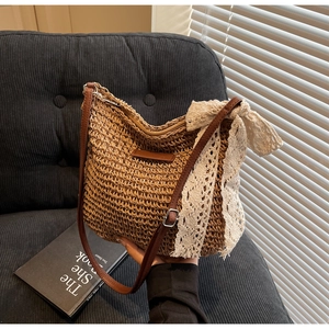Detailed close-up of woven straw bucket bag with lace bow and leather strap