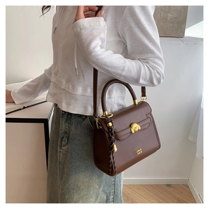 Brown crossbody bag with gold teddy bear buckle and leather texture on a model