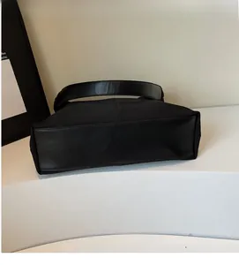 Detail showing soft black canvas fabric and leather handle of a minimalist tote bag