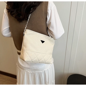 Detail of quilted cream nylon crossbody bag with metal chain strap and triangular logo