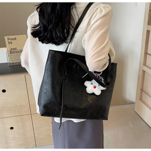 Detail of black tote bag with vintage embossed patterns and a plush star charm