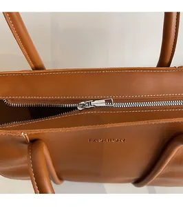 Close-up of smooth silver zipper and fine stitching on a brown leather tote bag