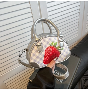 Detail der silbernen Metallic-Handtasche mit lila Karomuster und Erdbeerdruck