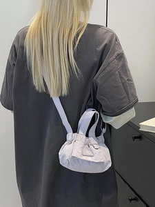 Minimalist light purple mini pleated bucket bag shown as a crossbody on a model back view