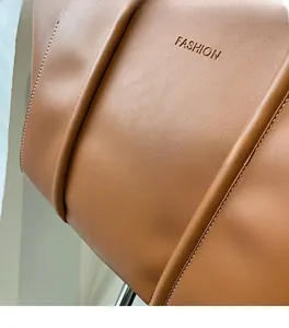 Close-up of brown leather tote bag with embossed fashion text and fine stitching details