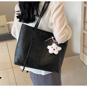 Detail of embossed Chinese characters on black leather tote bag with star plush charm