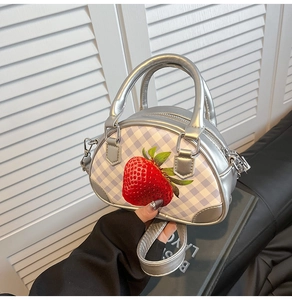 Detail der silbernen Handtasche mit lila Karomuster und rotem Erdbeerdruck-Motiv