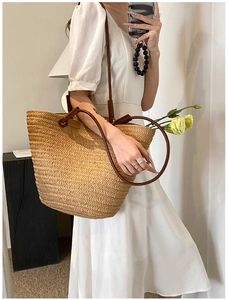 Detailed straw weave texture and brown leather handles of this stylish woven tote bag