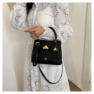 Detail of black leather handbag featuring golden lion head buckle and coih 2dn logo