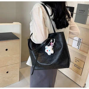 Detail view of large black embossed tote bag with white star plush charm accessory