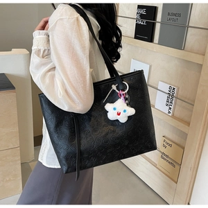 Detail of black embossed tote bag with Chinese characters and white plush star pendant