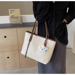 Detail of floral embossed tote bag with brown leather straps and star plush charm