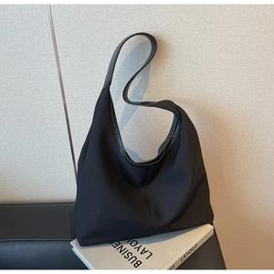 Close-up of black nylon hobo bag featuring wide shoulder strap and matte finish texture