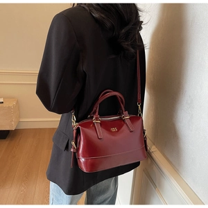 Deep burgundy Boston handbag in smooth leather finish shown on a model side view