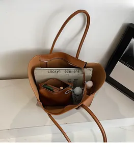 Detail of brown leather tote showing spacious interior with books and matching pouch