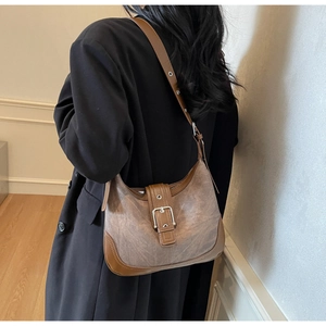 Vue détaillée d'un sac bandoulière demi-lune marron vintage avec boucle argentée sur mannequin